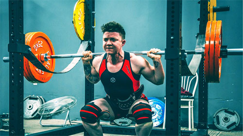 Young powerlifter squatting in meet